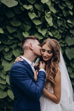 Güzel mutlu gelin ve damat düğün günü parkta poz veriyor.        