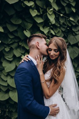 Güzel mutlu gelin ve damat düğün günü parkta poz veriyor.        
