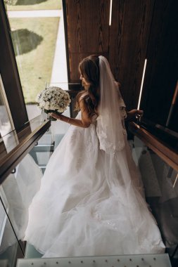 Beyaz elbiseli çekici bir gelin elinde bir buket düğün çiçeği tutuyor.                 