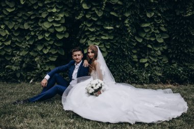 Güzel mutlu gelin ve damat düğün günü parkta poz veriyor.        