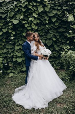 Güzel mutlu gelin ve damat düğün günü parkta poz veriyor.        