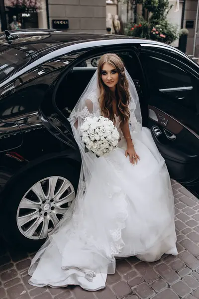 Bir buket çiçekli güzel gelin lüks bir arabayla geliyor.         