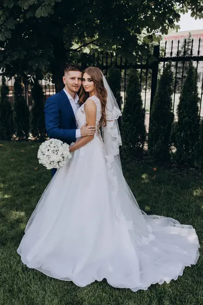 Güzel mutlu gelin ve damat düğün günü parkta poz veriyor.        