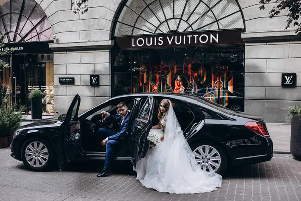 Mutlu gelin ve damat şehirde düğün gününde arabada poz veriyor..