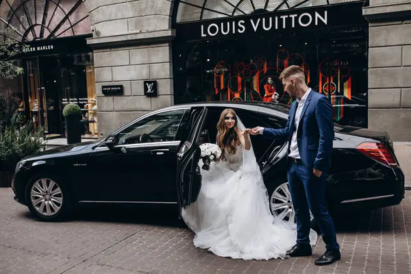 Mutlu gelin ve damat şehirde düğün gününde arabada poz veriyor..