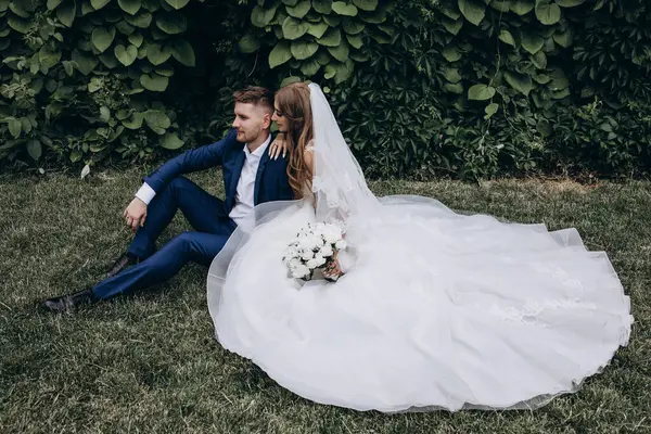 Güzel mutlu gelin ve damat düğün günü parkta poz veriyor.        