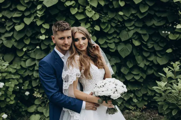 Güzel mutlu gelin ve damat düğün günü parkta poz veriyor.        