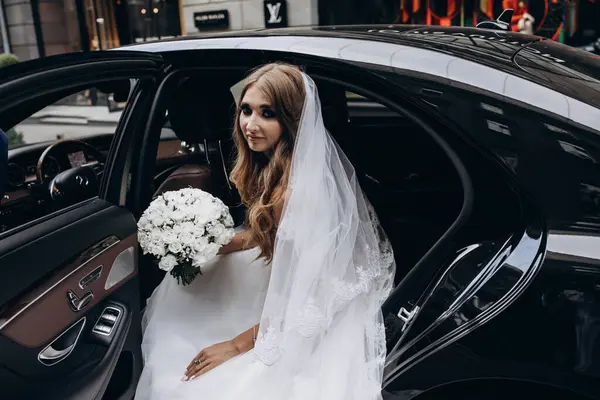 Bir buket çiçekli güzel gelin lüks bir arabayla geliyor.         