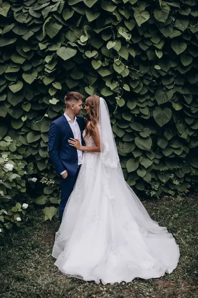 Güzel mutlu gelin ve damat düğün günü parkta poz veriyor.        