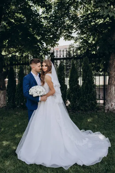 Güzel mutlu gelin ve damat düğün günü parkta poz veriyor.        