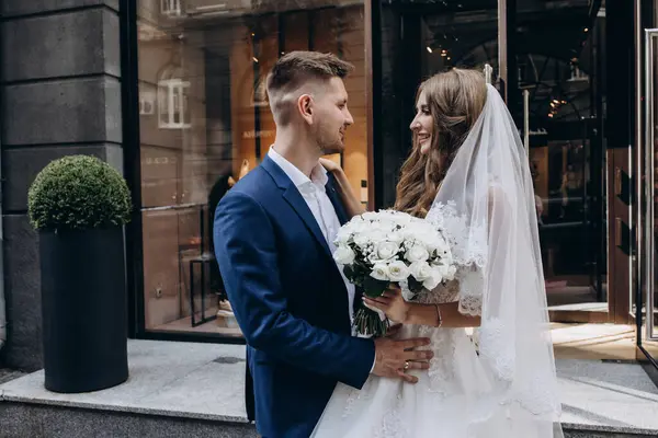 Güzel genç gelin ve damat düğün günü şehirde sarılıyor. 