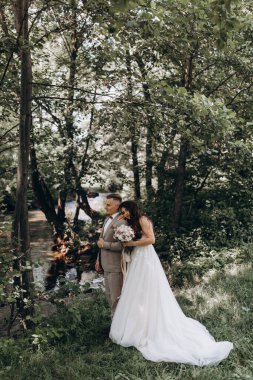 Güzel mutlu gelin ve damat gölün yakınındaki ormanda poz veriyor..          