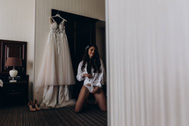 Güzel, mutlu, genç bir gelinin portresi. Sabahları gelinlikle evde poz veriyor.          