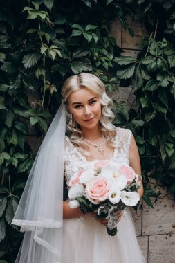 Parkta çiçek demeti tutan gelinlik içinde güzel bir gelin.         