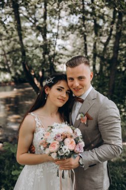 Güzel mutlu gelin ve damat gölün yakınındaki ormanda poz veriyor..          