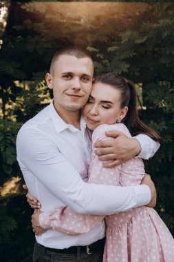 Genç ve güzel bir çift poz veriyor, bahçede sarılıyorlar.