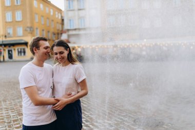 Genç ve mutlu bir çift çeşmenin yanında yürüyor ve eğleniyor.