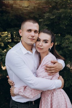 Genç ve güzel bir çift poz veriyor, bahçede sarılıyorlar.