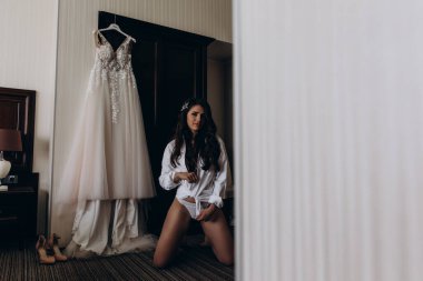 Güzel, mutlu, genç bir gelinin portresi. Sabahları gelinlikle evde poz veriyor.          