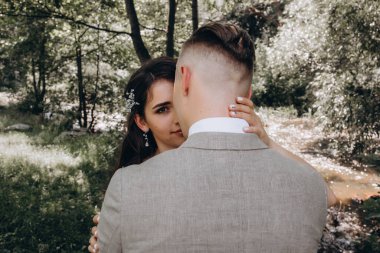 Güzel gelin ve damat düğün günü parkta sarılıp öpüşüyor..   