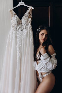 Çekici genç kız sabah beyaz dantelli gelinlikle poz veriyor.           