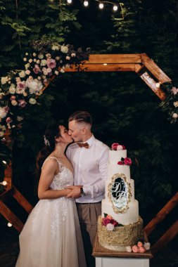 Gelin ve damat düğün töreninde düğün pastalarının yanında öpüşüyorlar.