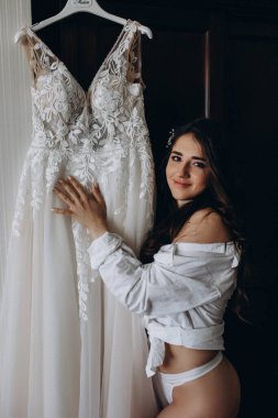Çekici genç kız sabah beyaz dantelli gelinlikle poz veriyor.           