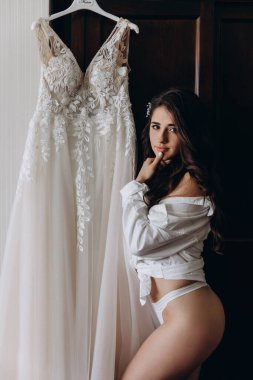 Çekici genç kız sabah beyaz dantelli gelinlikle poz veriyor.           