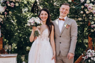 Düğün gününde dışarıda poz veren genç bir çift.