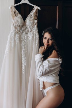 Çekici genç kız sabah beyaz dantelli gelinlikle poz veriyor.           