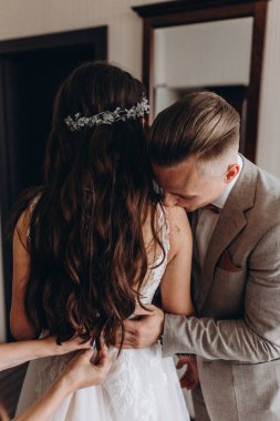 Genç ve güzel bir çift düğün gününde poz veriyor, damat gelininin omzunu öpüyor. 