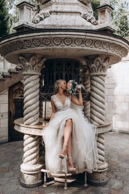 Gelinlik içinde oturan ve elinde bir buket çiçek tutan genç gelin.