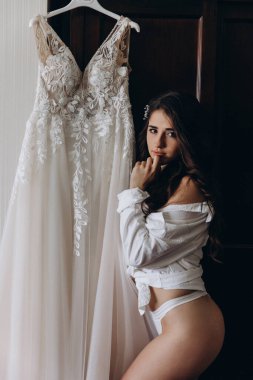 Çekici genç kız sabah beyaz dantelli gelinlikle poz veriyor.           