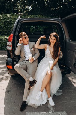 Güzel bir çift yeni evli arabada poz veriyor. Kokain içiyor, eğleniyor. Gelin ise bisepslerini damada gösteriyor.