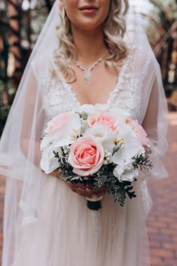 Yakından bakınca genç gelinin elinde güzel bir düğün buketi tuttuğunu görüyoruz..