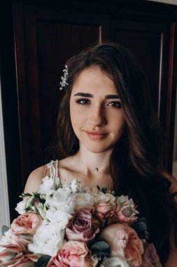 Beyaz elbiseli çekici bir gelin elinde bir buket düğün çiçeği tutuyor.                 