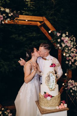 Gelin ve damat düğün töreninde düğün pastalarının yanında öpüşüyorlar.