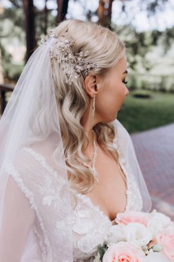 Parkta çiçek demeti tutan gelinlik içinde güzel bir gelin.         