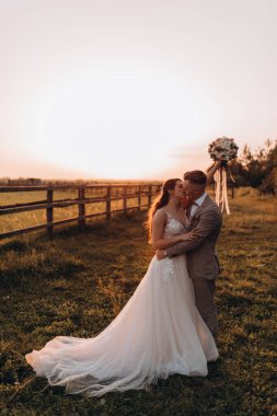 Gün batımında dışarıda poz veren mutlu genç bir çift.       