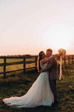 Gün batımında dışarıda poz veren mutlu genç bir çift.       