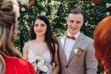 Genç, güzel bir düğün çifti gülümsüyor ve misafirlerini karşılıyor..