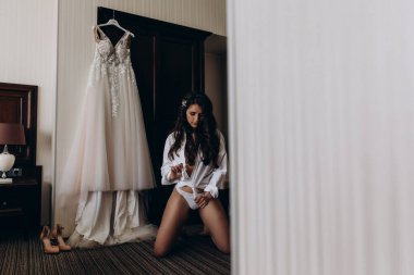 Çekici genç kız sabah beyaz dantelli gelinlikle poz veriyor.           