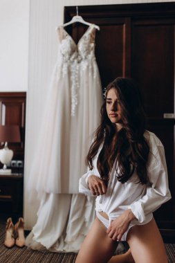 Çekici genç kız sabah beyaz dantelli gelinlikle poz veriyor.           