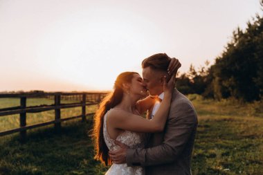 Gün batımında dışarıda poz veren mutlu genç bir çift.       