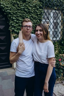 Açık havada beyaz tişört giyen mutlu bir çiftin portresi.