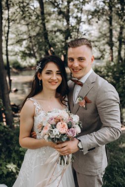 Güzel mutlu gelin ve damat gölün yakınındaki ormanda poz veriyor..          