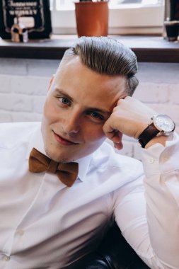 Genç yakışıklı adam kameraya bakarken papyon takıyor.