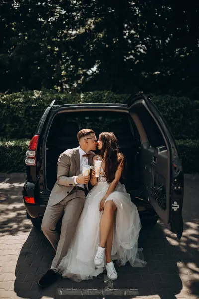 Güzel bir çift yeni evli arabada poz veriyor kola içiyor, öpüşüyor. 
