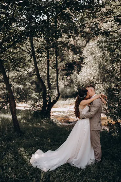 Güzel gelin ve damat düğün günü parkta sarılıp öpüşüyor..   