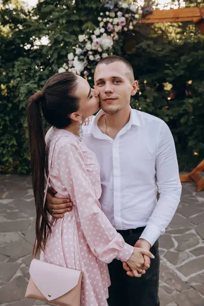 Genç ve güzel bir çift bahçede poz veriyor, kadın kocasını öpüyor. 